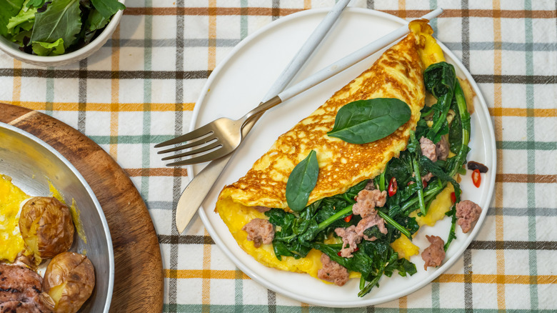 Omelet filled with spinach on white plate