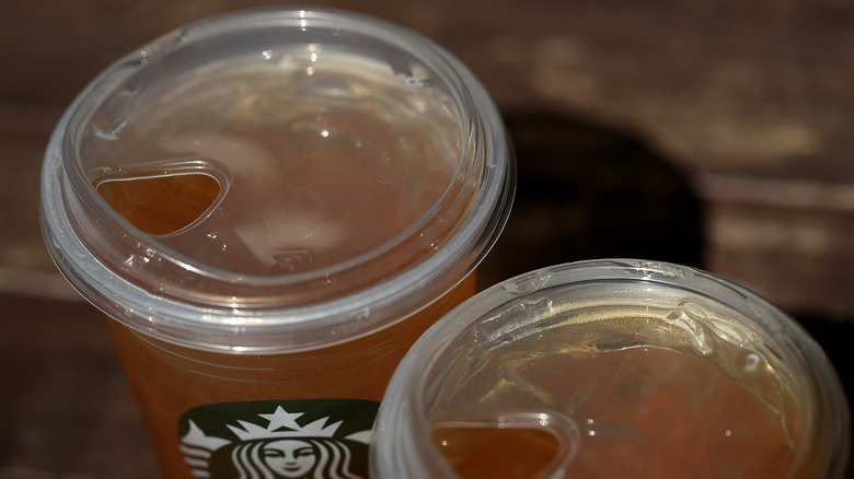 A pair of Starbucks cold drinks topped with the clear plastic sipping lids