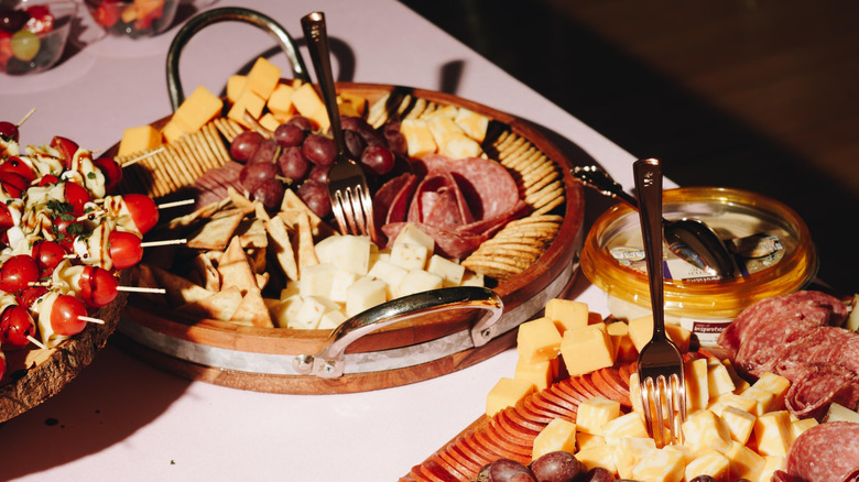 Cheese, crackers, and meat arranged on wooden serving trays on a table