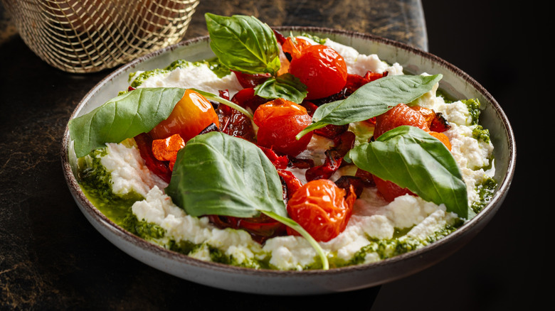 Creamy whipped feta cheese topped with roasted cherry tomatoes, fresh basil, and herb oil