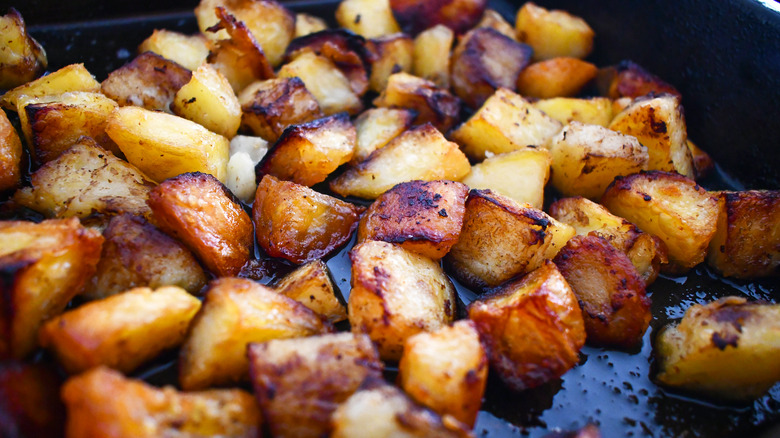 Roasted potato wedges with sprinkled spices and herbs on cream colored paper