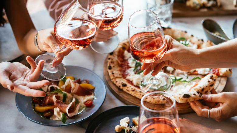 wine glasses cheers over a feast of Italian dishes