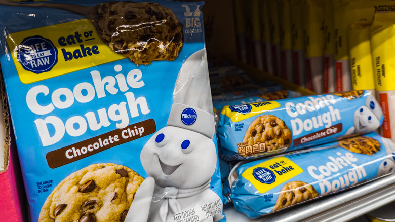 Pillsbury chocolate chip cookie dough products in refrigerated section at grocery store.