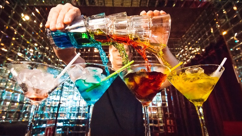 Bartender pouring multiple colorful drinks at once