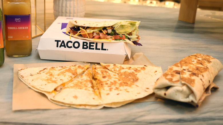 A Taco Bell burrito, soft taco, and Crunchwrap on a marble countertop