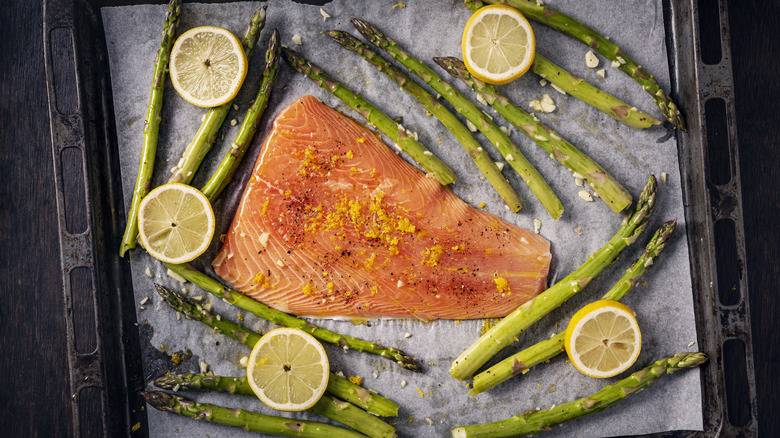 Salmon, asparagus, and lemons on a sheet pan covered with parchment paper