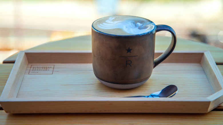 Elegant latte in Starbucks Roastery mug on wood tray