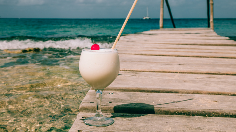 A pina colada garnished a cherry on a beach boardwalk