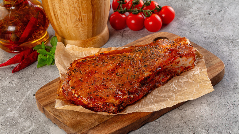 Marinated meat laying on a piece of paper on small wooden board
