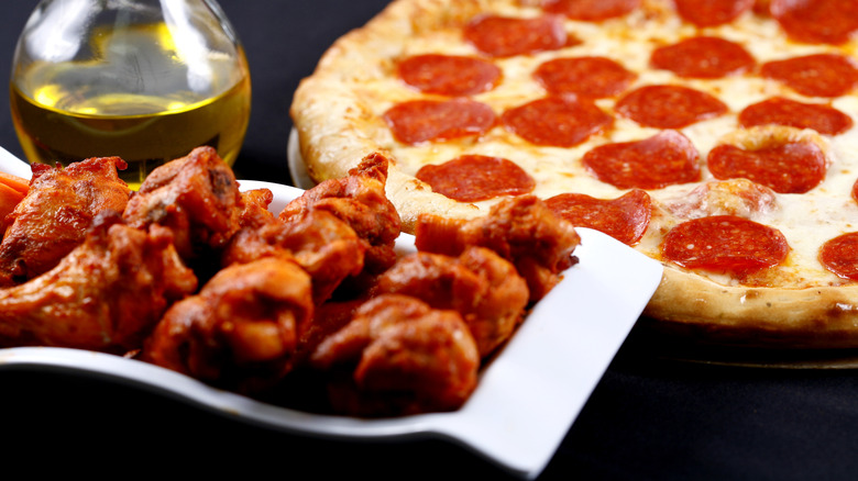 Buffalo wings in front of a pepperoni pizza