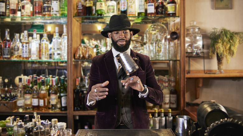 Bartender in hat throwing cocktail shaker