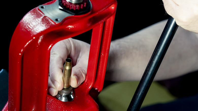 Hand using gunpowder press for ammunition