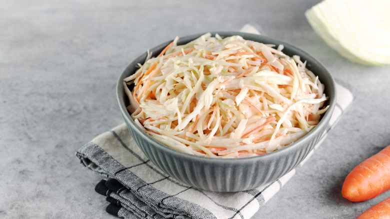 Bowl of cabbage and carrot coleslaw sitting on a folded towel