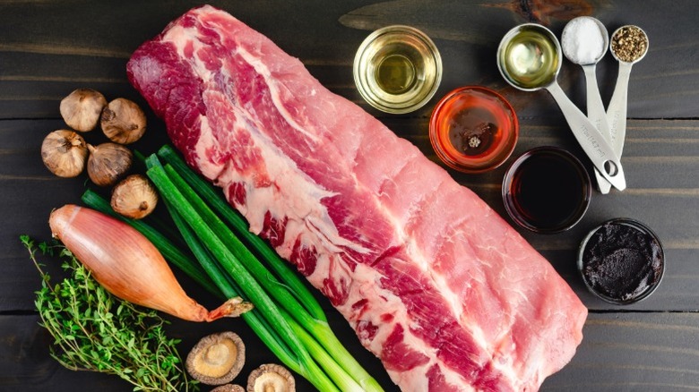 A rack of baby back ribs next to various aromatics.