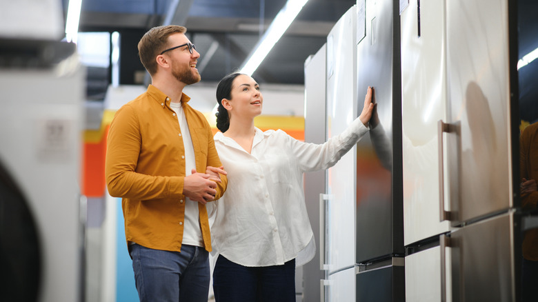 Couple shops for refrigerator in store