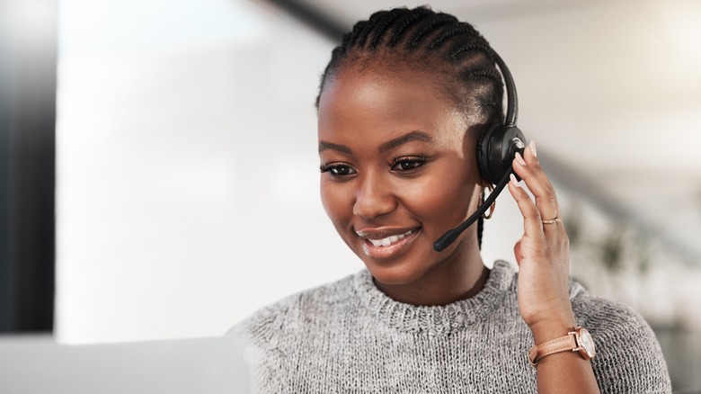 Smiling woman with headset sits at computer