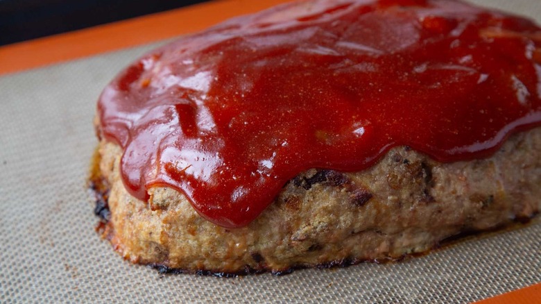 Meatloaf glazed with ketchup on baking sheet