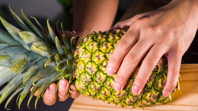 Two hands holding a pineapple
