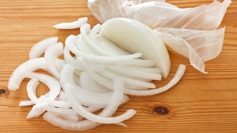 A sliced white onion on a wooden cutting board.