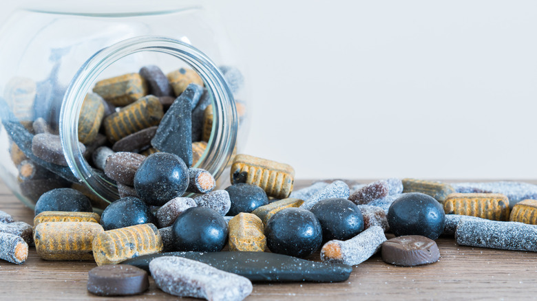 A jar of salty licorice candies spilling onto a table