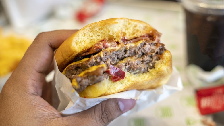 Person holding half-eaten burger