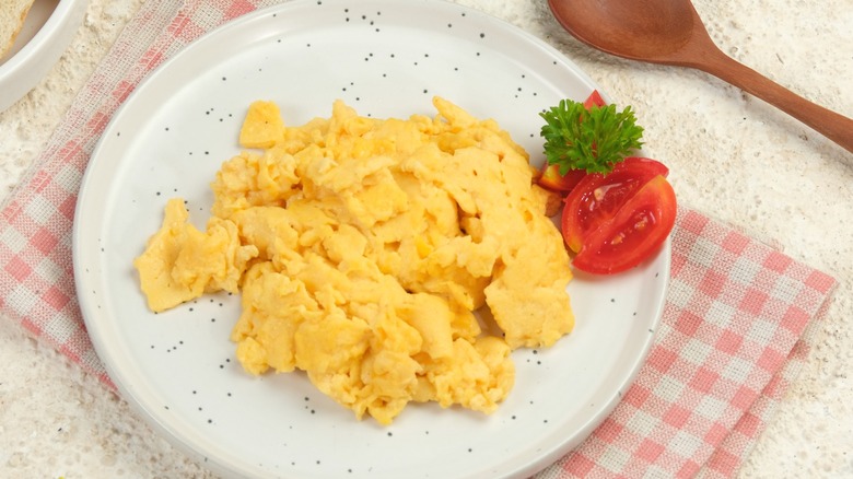 Scrambled eggs garnished with sliced tomato.