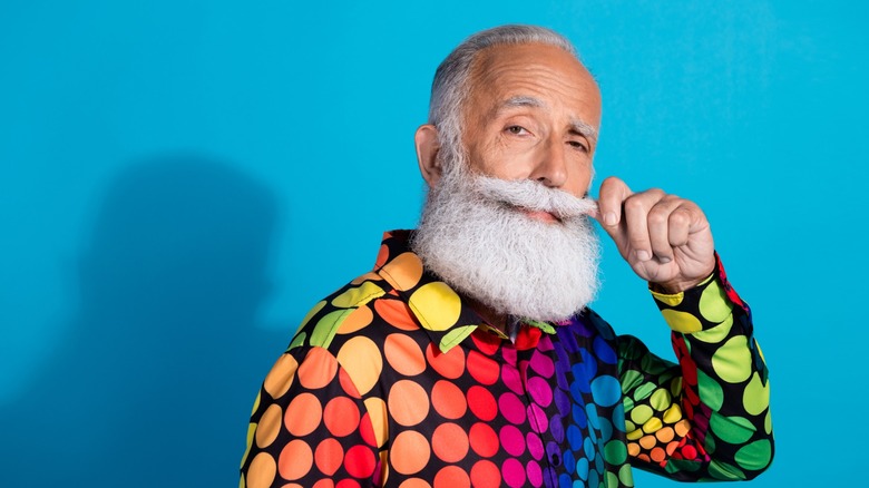 Photo of eccentric man touching his mustache wearing a colorful shirt
