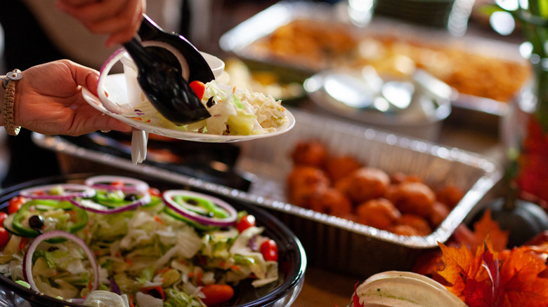 salad being served with tongs on a buffet