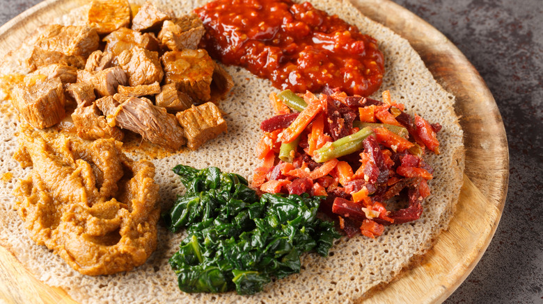 teff injera topped with meats and vegetables