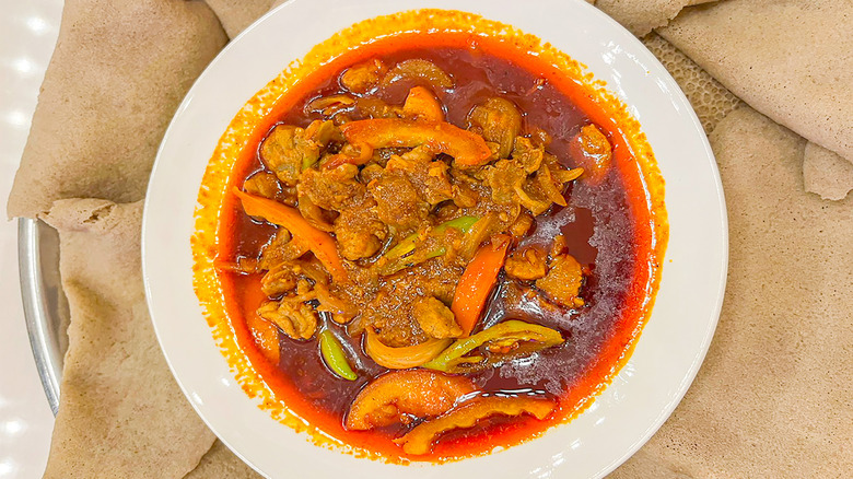 doro wat in a white bowl surrounded by injera