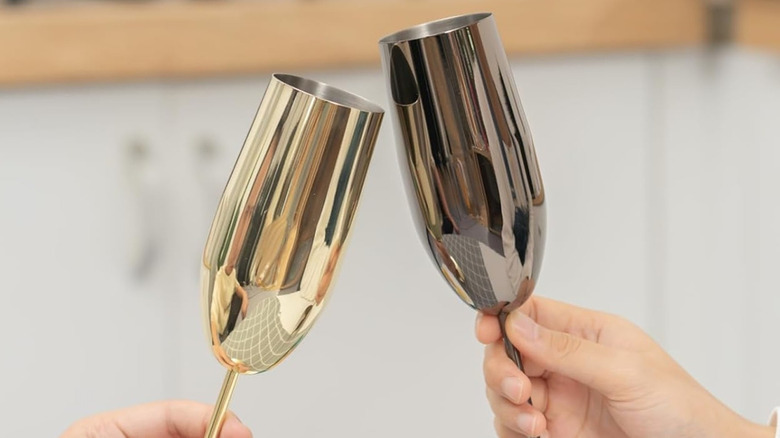 Two hands toasting with metallic Champagne flutes