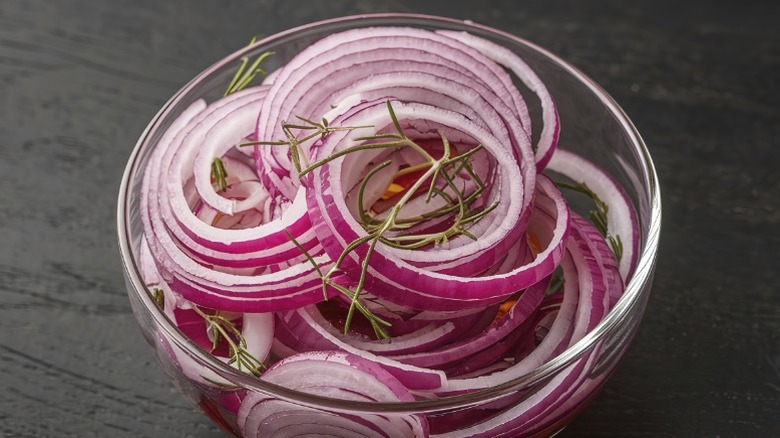 A glass bowl full of red onion slices.