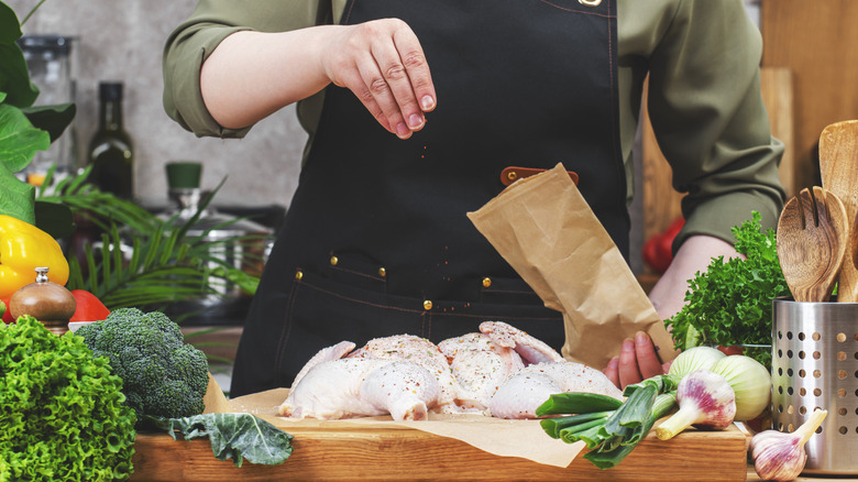 A person seasons chicken using a proper technique