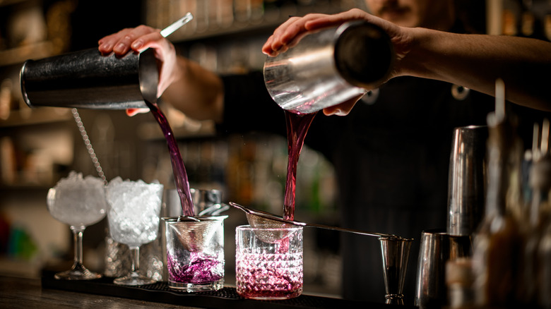 Bartender pouring two cocktails from both halves of the shaker.
