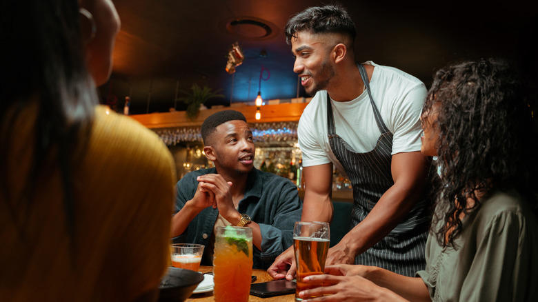 Waiter serving drinks to a table of restaurant customers