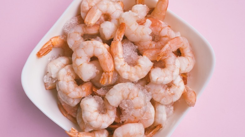 A bowl of healthy pink shrimp with tails on and shells removed.