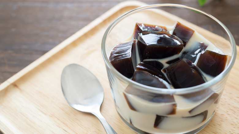 Coffee jelly with cream on a wooden tray with a spoon