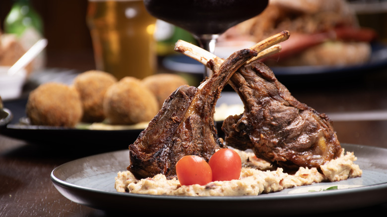 Two tomahawk steaks on a bed of mashed potatoes with full spread in background