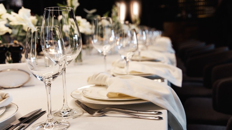 Table settings with stem glasses, silverware, and white flowers at a fine dining restaurant