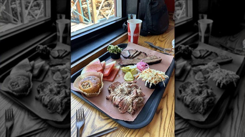 A black tray lined with brown paper with barbecued meat and sides