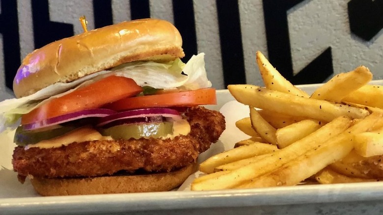 A close-up of a breaded pork tenderloin sandwich on a metal tray