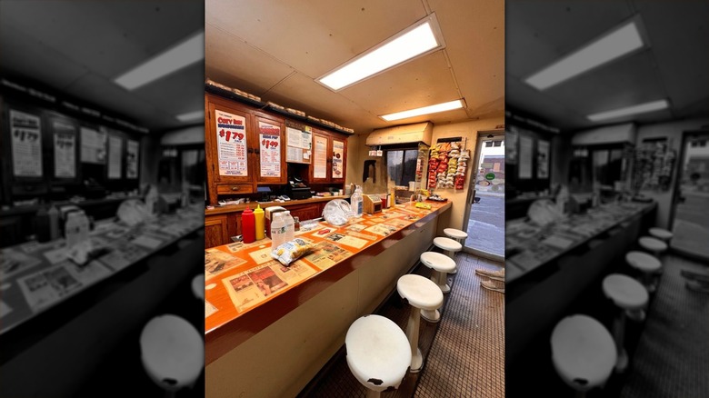 An old-fashioned lunch counter lined with five white backless stools