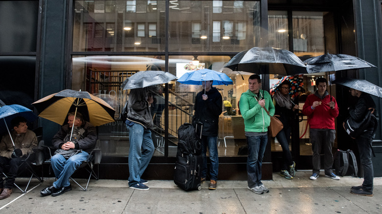 A group of people with umbrellas standing in line on a city street