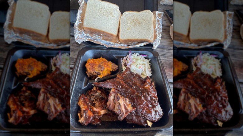 Ribs, brisket, coleslaw, and sweet potato casserole in a to-go container wiht two slices of white bread