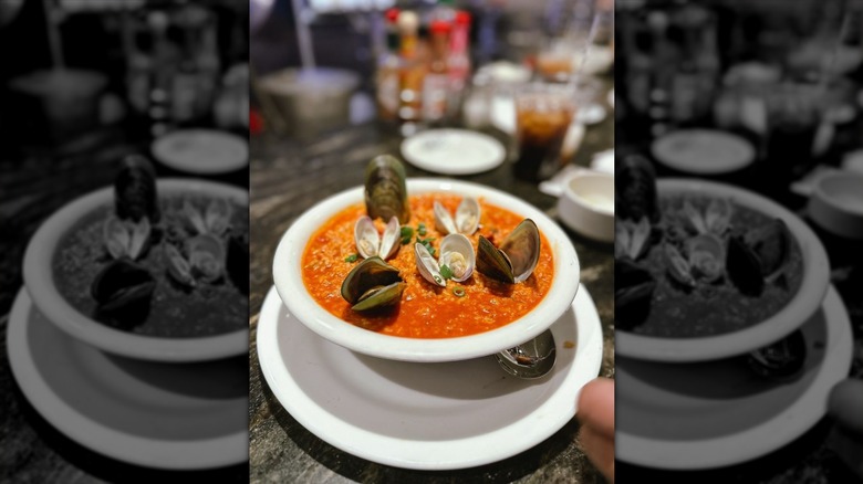 Seafood jambalaya with open clam shells on top in a white bowl at The Oyster Bar at Palace Station