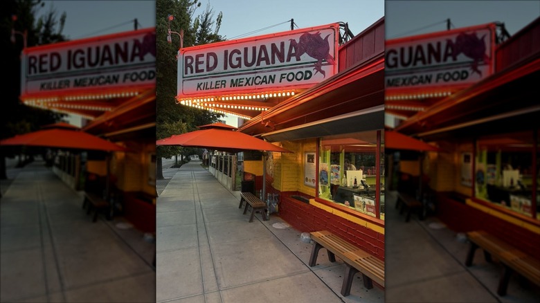 The exterior of a Red Iguana at dusk; red and white sign is lit with marquis lights