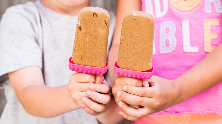 Two kids holding up frozen chocolate pops