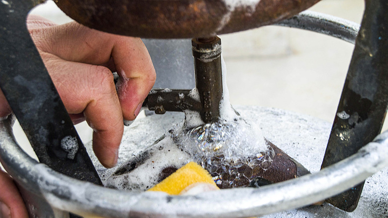 Close-up of a propane tank valve in front of a gas grill.