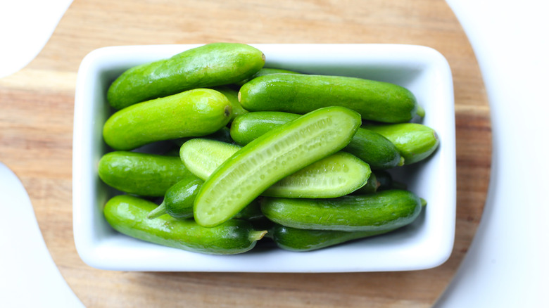mini cucumbers in a white dish on a wooden board