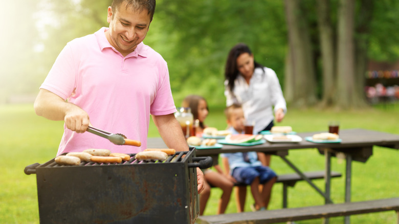 Family grilling sausages at public park